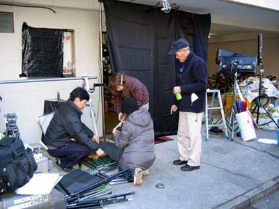 オミノショップの外では夜のシーンの撮影のために暗幕を準備しているスタッフ